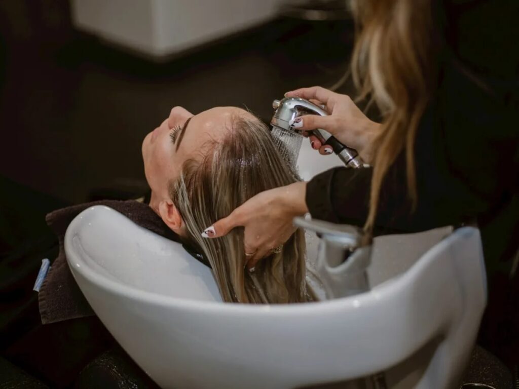 Stylist washing a woman's hair in a salon