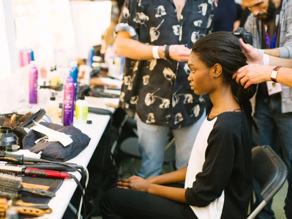 Woman sitting in a chair at a salon while stylists work on her hair