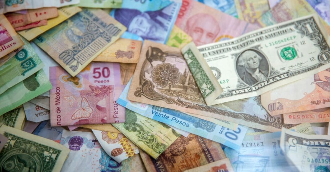 Paper currency from various countries strewn on a desk