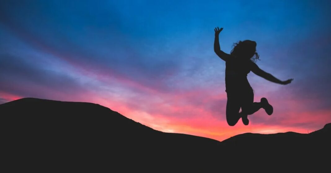 Woman jumping in the air backlit by the setting sun